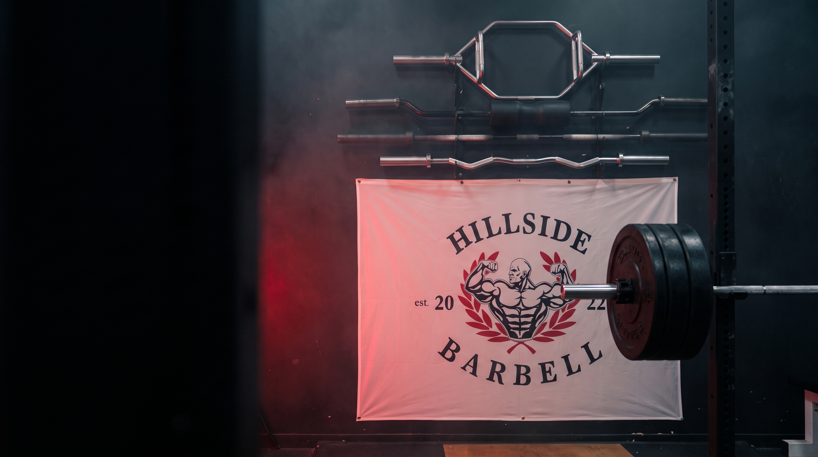 Hillside Barbell gym interior — specialty barbells and the Hillside Barbell banner under dramatic red light